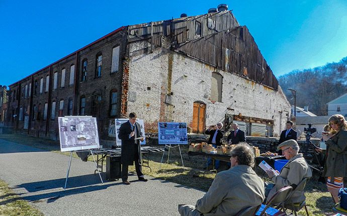 A crowd holds a presentation in front of an old Brownfields buidling.