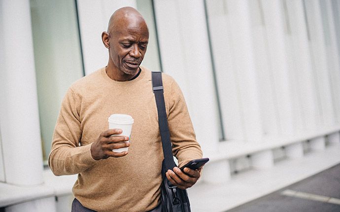 Man looking at phone with shoulder bag